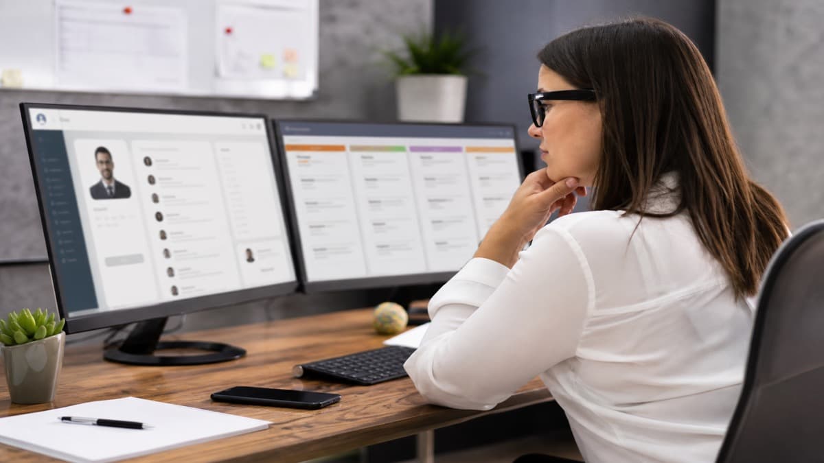 Laptop on a standing desk showing a resume parse preview next to a printed page and a glass of water